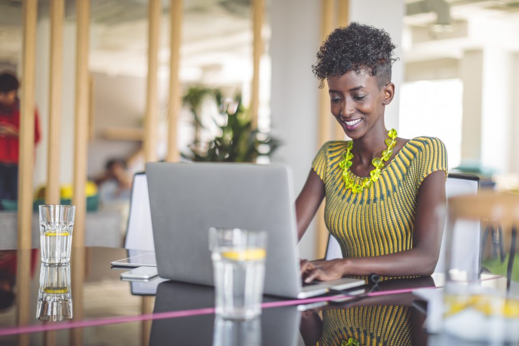 Black Woman Smiling and Working on a Laptop - 10 brilliant ideas for making money without a job