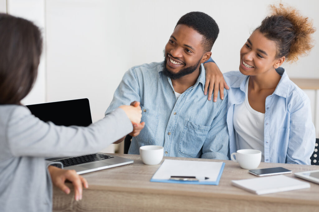 smiling spouses handshaking with insurance saving money