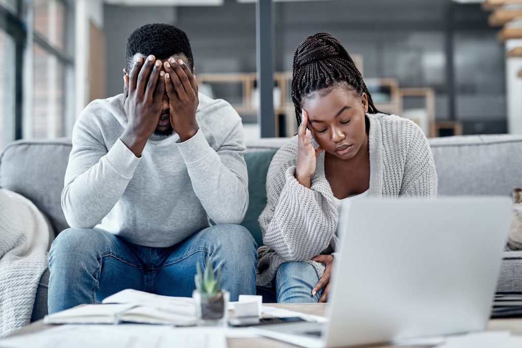 A black man and woman look disturbed after mistakes in investing